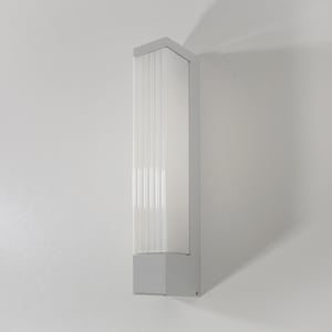 May include: A white wall-mounted light fixture with a rectangular shape and a frosted glass diffuser. The light fixture has a modern design and is ideal for outdoor use.