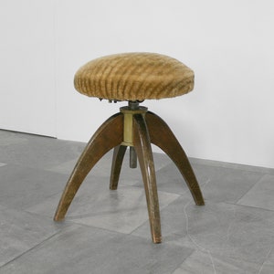 May include: A brown, adjustable height stool with a plush, ribbed fabric seat and a wooden base with three legs.