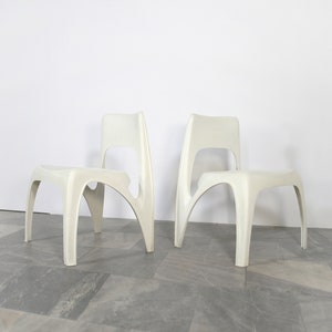 Puede incluir: Dos sillas blancas de plástico con un diseño moderno y único. Las sillas tienen una forma curva y orgánica con un respaldo alto y cuatro patas.