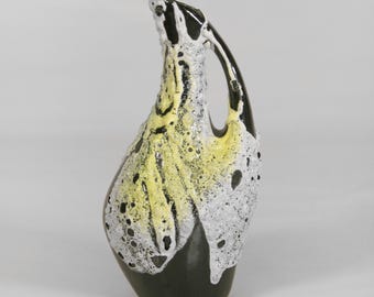 May include: A ceramic jug with a distinctive design. It has a black base, a textured body in white and yellow, and a black handle. The design incorporates speckled details and a glossy finish, creating a striking contrast.