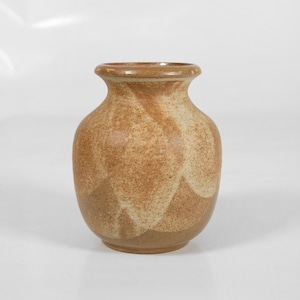 May include: A small, brown ceramic vase with a white glaze pattern. The vase has a rounded body and a slightly flared lip.