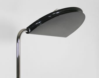 Może przedstawiać: Czarna i srebrna lampa stojąca z zakrzywionym, półkolistym kloszem. Lampa jest wykonana z metalu i ma prosty, nowoczesny design.