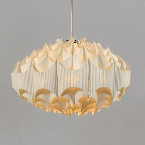 May include: A white, multi-layered, pendant light fixture with a geometric design. The light fixture is made of a material that resembles paper or fabric.