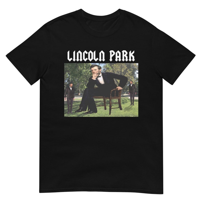 May include: Black t-shirt with a white graphic print of a man sitting on a chair in a park. The text "LINCOLN PARK" is printed in white above the graphic.