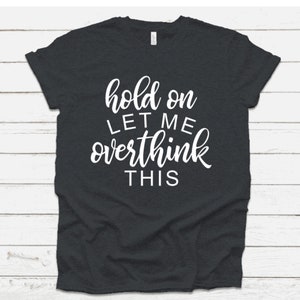 May include: Dark gray t-shirt with white text that reads "hold on let me overthink this".