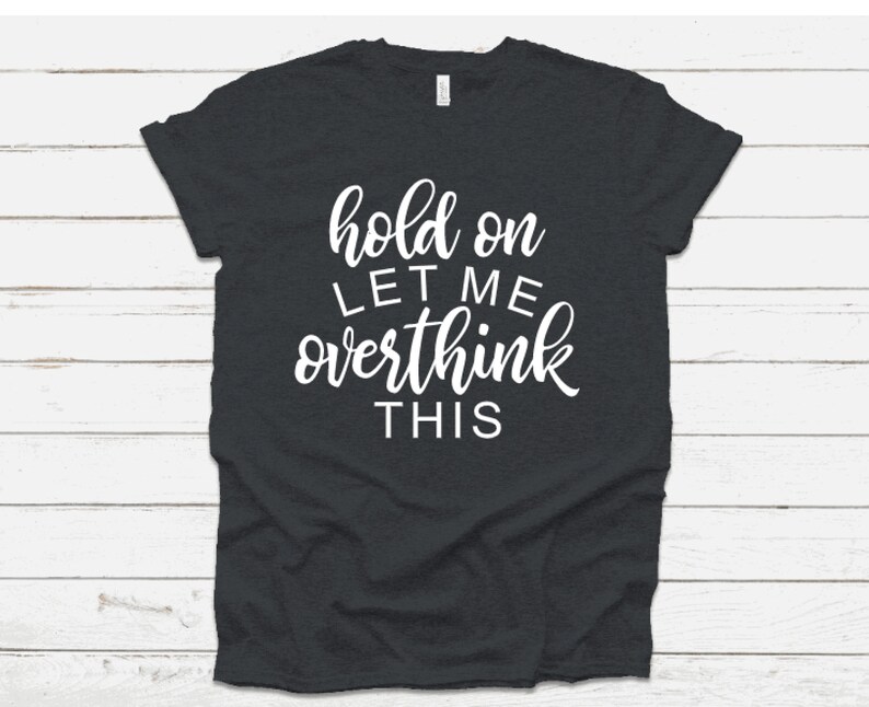 May include: Dark gray t-shirt with white text that reads "hold on let me overthink this".