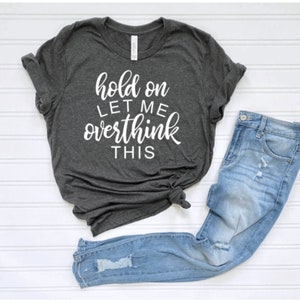 May include: A dark gray t-shirt with the text "hold on let me overthink this" in white lettering.
