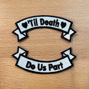 May include: Two white embroidered patches with black outlines. The top patch says "'Til Death" with a heart on each side. The bottom patch says "Do Us Part".