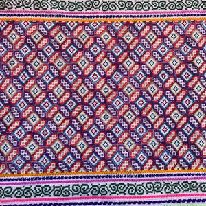 May include: A white fabric with a colorful geometric pattern woven into the fabric. The pattern is made up of small squares and diamonds in shades of red, blue, green, yellow, and purple.