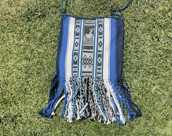 May include: A blue and white woven tapestry with fringe. The tapestry has a geometric pattern and is made of a soft, textured fabric.