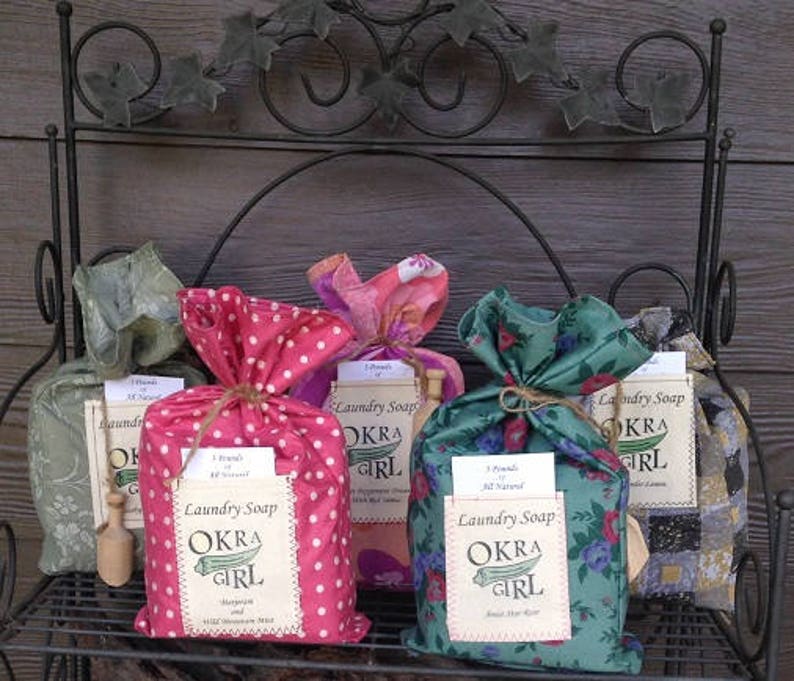 May include: Three bags of laundry soap, each wrapped in a different patterned fabric. The bags are labeled "Laundry Soap Okra Girl" and are all natural.