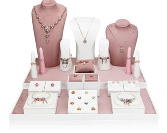 May include: A jewelry display set featuring three velvet-covered necklace busts, multiple ring cones, and white platforms. The collection includes silver and rose gold necklaces, charm bracelets, rings, and various small decorative charms.