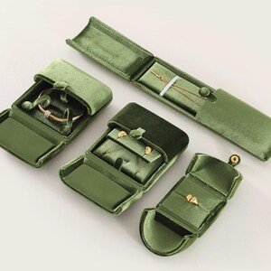 May include: A collection of four olive green velvet jewelry boxes in various shapes and sizes. The set includes a long rectangular case, a square box, a small ring box, and a larger square box, all featuring soft velvet linings and snap closures.