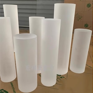 May include: A set of six frosted acrylic cylinders of varying sizes. The cylinders are all white and opaque.