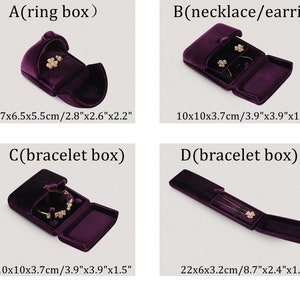 Op de afbeelding: Vier donkerpaarse fluwelen sieradendoosjes worden getoond. De doosjes zijn gelabeld voor ringen, kettingen/oorbellen en armbanden. Afmetingen worden weergegeven in cm en inches. De doosjes zijn open en tonen sieraden.