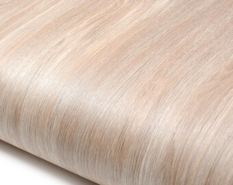 May include: Close-up of a roll of light-colored wood-grain contact paper. The paper has a smooth, slightly glossy finish with a subtle pattern of wood grain. The color is a warm, neutral tone, suitable for various home decor projects.