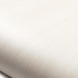 May include: A smooth, off-white surface featuring a subtle, linear wood grain pattern that runs diagonally across the frame. The texture appears uniform and light in color, with soft shadows creating a gentle curve along the bottom edge.