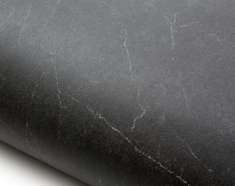 May include: Close-up of a dark gray, textured surface with subtle white veining. The material appears to be rolled, revealing its thickness and flexibility. The surface has a matte finish.