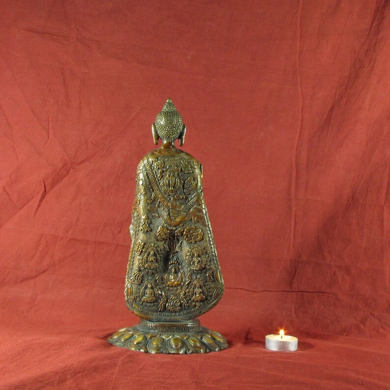 May include: A gold-coloured metal statue of Buddha, standing on a circular base. The statue is intricately detailed with carvings and designs.