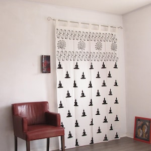 May include: White cotton curtains with a black and white print of meditating figures and trees. The curtains are hung on a white rod with silver hooks.