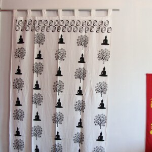 May include: White cotton curtain with a black and white print of repeating Buddha figures and trees. The curtain has a decorative border of small squares.