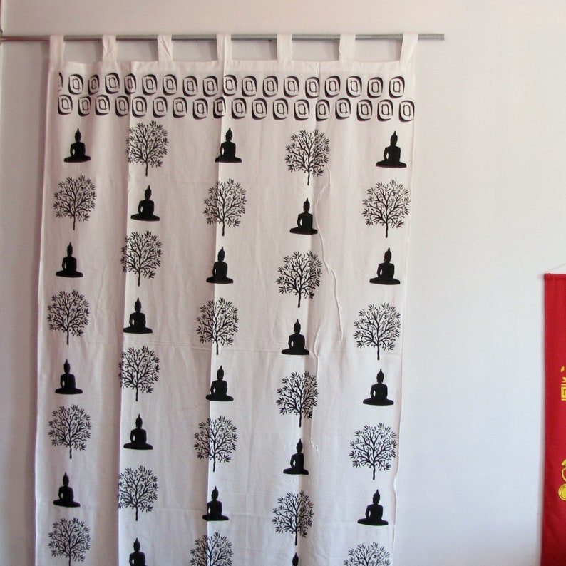 May include: White cotton curtain with a black and white print of repeating Buddha figures and trees. The curtain has a decorative border of small squares.
