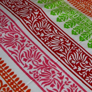 Pu&ograve; includere: Tessuto bianco con strisce colorate di motivi floreali. Le strisce sono in tonalit&agrave; di arancione, rosa, rosso e verde.