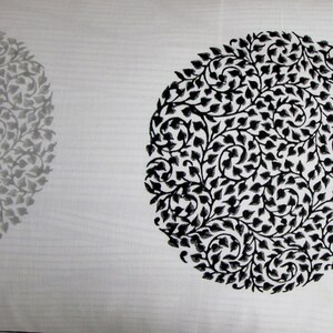 May include: White fabric with a black and gray floral pattern. The pattern is in the shape of a circle.