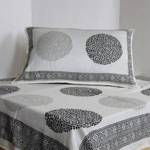 May include: White cotton bedding with a black and gray floral print. The bedding features a pillowcase with a black and gray floral design and a matching flat sheet with a black and gray floral design.