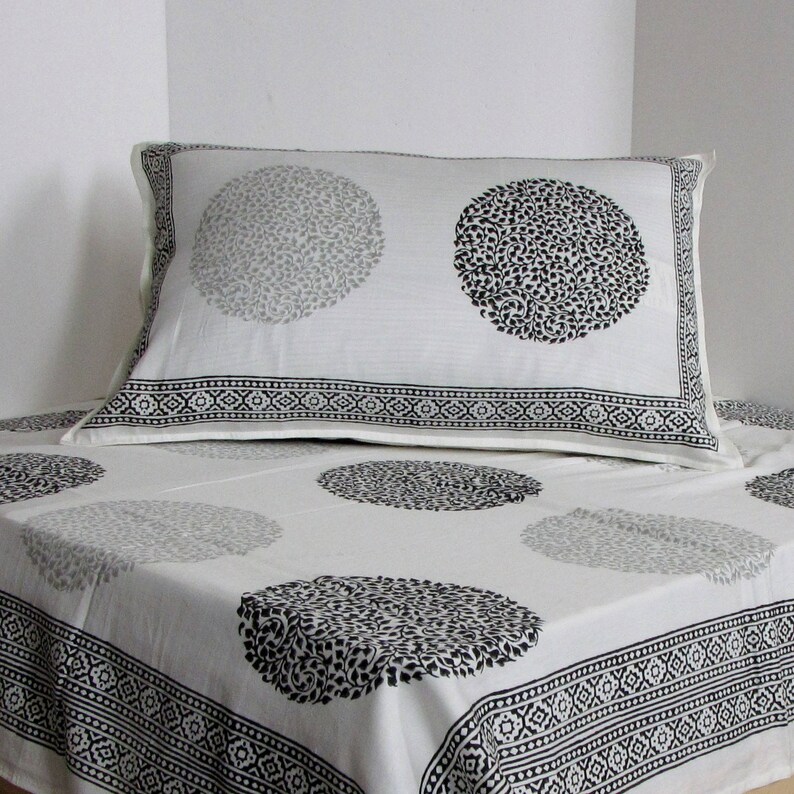 May include: White cotton bedding with a black and gray floral print. The bedding features a pillowcase with a black and gray floral design and a matching flat sheet with a black and gray floral design.