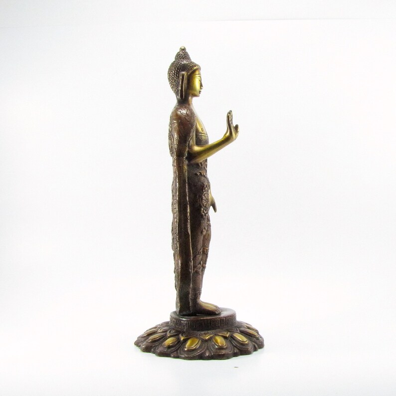 May include: A gold and brown metal statue of a standing Buddha with a lotus base. The Buddha is wearing a robe and has a serene expression.