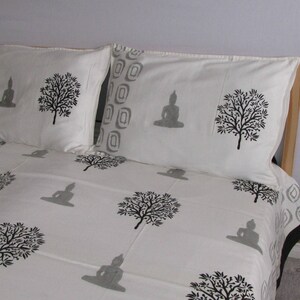 May include: White cotton bedding with a gray and black print of trees and meditating figures. The bedding includes a flat sheet and two pillowcases.