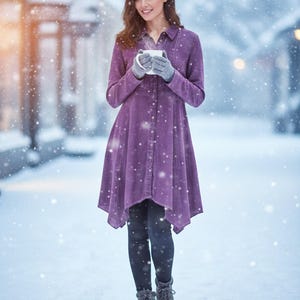 May include: A person wearing a long-sleeved, button-down purple dress and grey gloves, holding a white mug. They are standing in a snowy environment, wearing black leggings and grey boots. The dress has a flared hem.