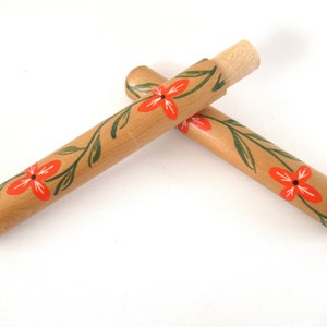 Puede incluir: Dos estuches de madera para agujas con un dise&ntilde;o floral. Los estuches est&aacute;n pintados con flores naranjas y hojas verdes.