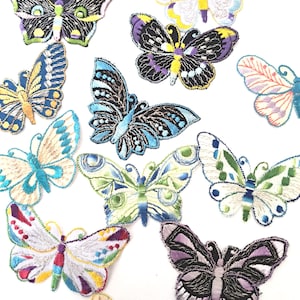 Pode incluir: Uma coleção de patches de borboletas bordadas em várias cores. Os patches apresentam costuras detalhadas em tons de azul, verde, roxo, amarelo e vermelho. Cada borboleta tem um design único, com padrões intrincados nas asas.