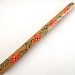 Puede incluir: Un taco de madera con un dise&ntilde;o floral pintado en &eacute;l. Las flores son rojas y las hojas son verdes.