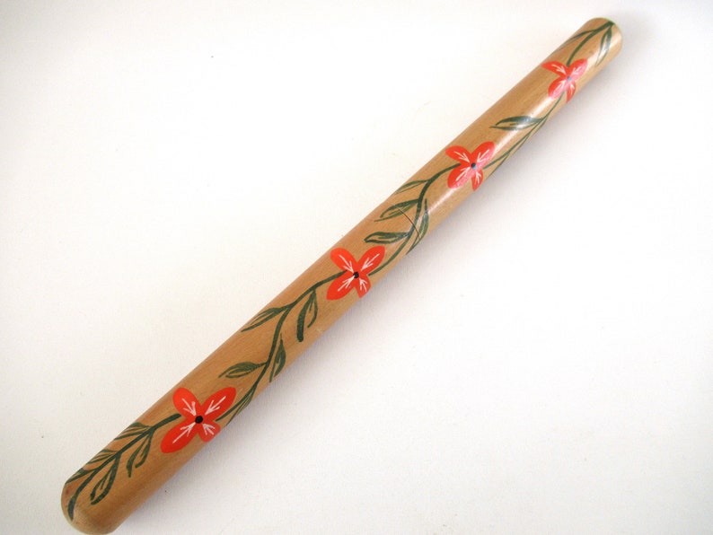 Puede incluir: Un taco de madera con un dise&ntilde;o floral pintado en &eacute;l. Las flores son rojas y las hojas son verdes.