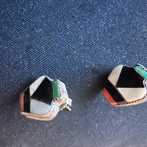 Puede incluir: Un par de pendientes de botón geométricos. Cada pendiente presenta un diseño de mosaico con piedras incrustadas negras, blancas, rojas y verdes engastadas en un marco de metal plateado. Los pendientes tienen cierre de poste y mariposa.