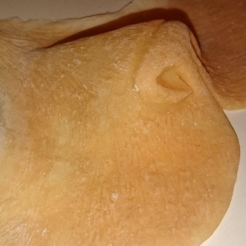 Peut inclure: Gros plan sur un objet textur&eacute; brun clair avec un bord incurv&eacute; et un petit d&eacute;tail en retrait. La surface a un aspect l&eacute;g&egrave;rement rugueux, avec de subtiles variations de couleur et de texture.