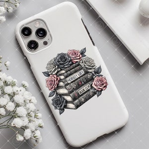 May include: White phone case with a stack of books and flowers. The books have the text "Morally Grey Book Club" on the spine. The flowers are black, white, and pink.