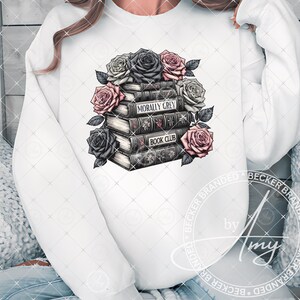 May include: White sweatshirt with a graphic of a stack of books with the text "Morally Grey Book Club" and pink and black roses.