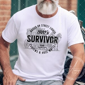 May include: A white t-shirt with a black and gray graphic design featuring a horse-drawn carriage and the text "Raised on Street Lights 1900's Survivor The Good Life Curfews & Hose Water".