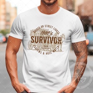 May include: A white t-shirt with a brown graphic design featuring a horse-drawn carriage and the text "Raised on Street Lights 1900's Survivor The Good Life Curfews & Hose Water".