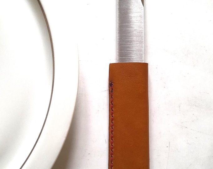 The Le Tranchet table knife, basic version, is a steak knife with an asymmetrical blade and a leather handle.