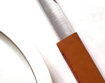 The Le Tranchet table knife, basic version, is a steak knife with an asymmetrical blade and a leather handle.