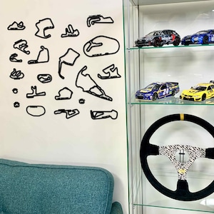 May include: Black wall decals of race tracks in various shapes and sizes. A glass display case holds model race cars and a black steering wheel with a patterned center.