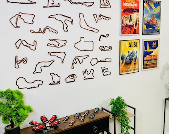 May include: A wall display featuring brown wooden race track outlines and vintage racing posters. A black console table holds miniature race cars and a decorative flower. The posters include the words "Monaco", "Albi", and "San Sebastian".