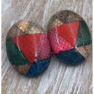 May include: A pair of oval-shaped earrings featuring a patchwork design of textured snakeskin-patterned leather in vibrant shades of red, pink, blue, green, and beige. Each earring is composed of multiple triangular segments arranged in a geometric pattern.