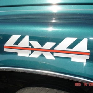 Puede incluir: Un guardabarros de vehículo turquesa muestra un emblema "4X4" blanco y rojo. El emblema está delineado en blanco con una franja horizontal roja. La fecha "AUG 14 2007" es visible en la esquina inferior derecha.