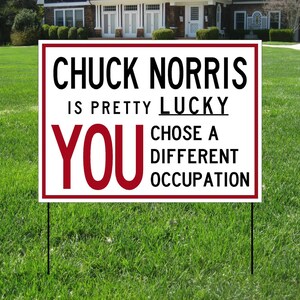 May include: White yard sign with black text that reads "Chuck Norris is pretty lucky you chose a different occupation". The word "you" is in red.